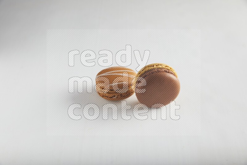 45º Shot of of two assorted Brown Irish Cream, and Yellow, and Brown Chai Latte macarons on white background