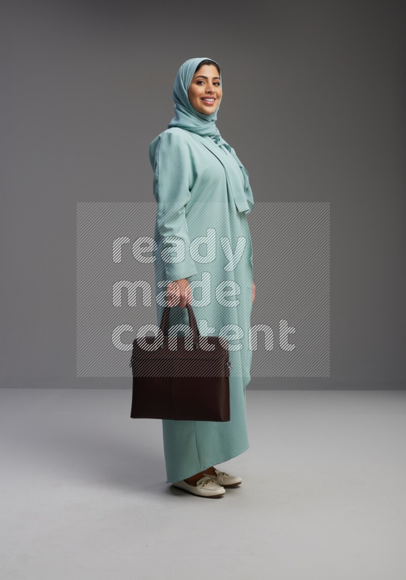 Saudi Woman wearing Abaya standing holding bag on Gray background