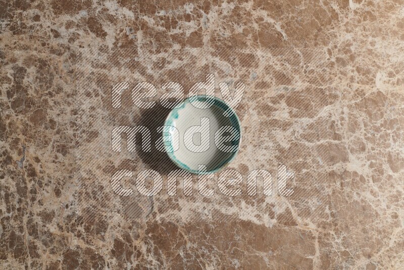 A multicolored pottery bowl on beige marble background