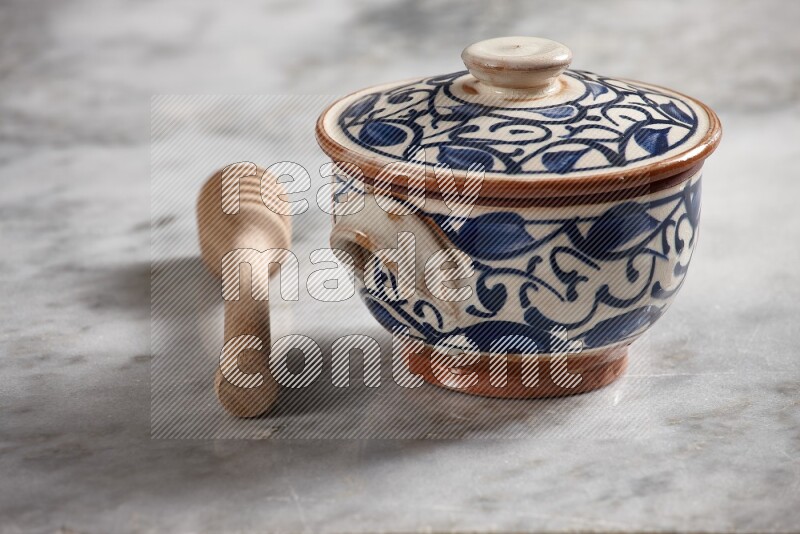 Decorative pottery pot with wooden honey dipper on the side on grey marble background