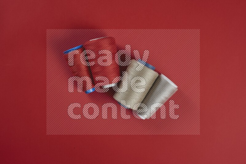 A brown and red collection of sewing and tailoring tools arranged on a red background