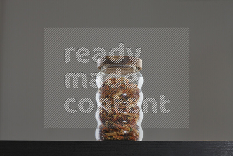 Chili pepper in a glass jar on black background