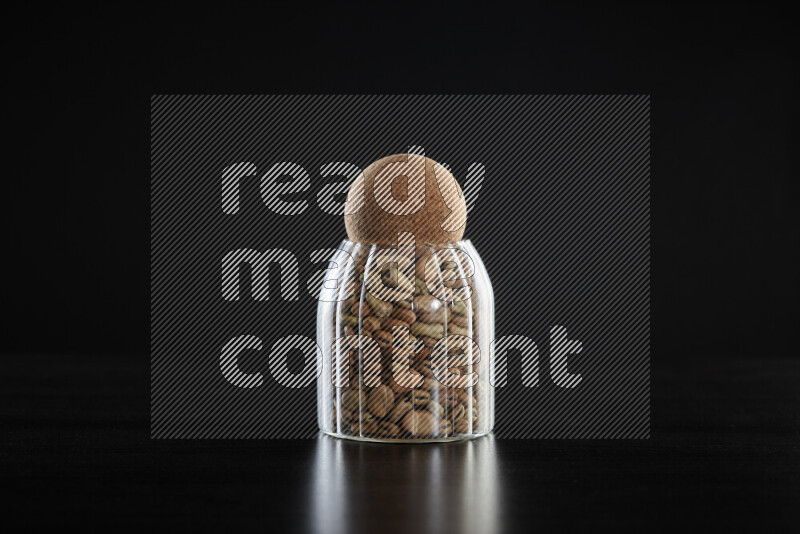 Fava beans in a glass jar on black background