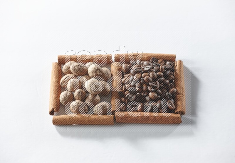 مربعان من أعواد القرفة ممتلئان بحبوب القهوة وجوزة الطيب علي خلفية بيضاء