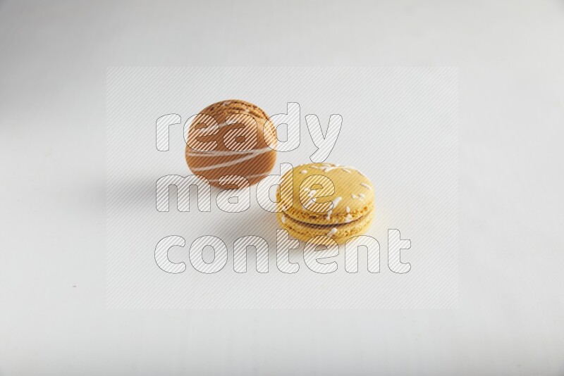 45º Shot of of two assorted Brown Irish Cream, and Yellow Piña Colada macarons on white background