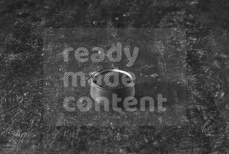 وعاء فخاري أسود ممتلئ ببذور حبة البركة علي خلفية سوداء