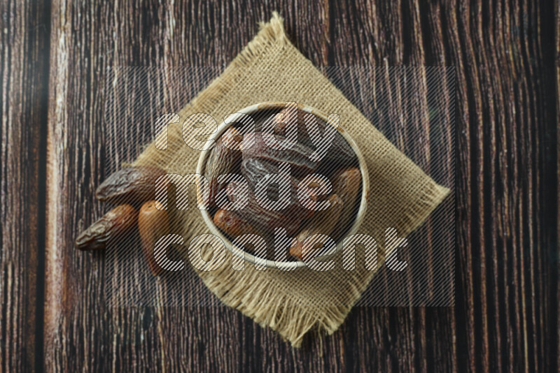 Dates in different bowls (wooden, pottery and glass) on wooden background