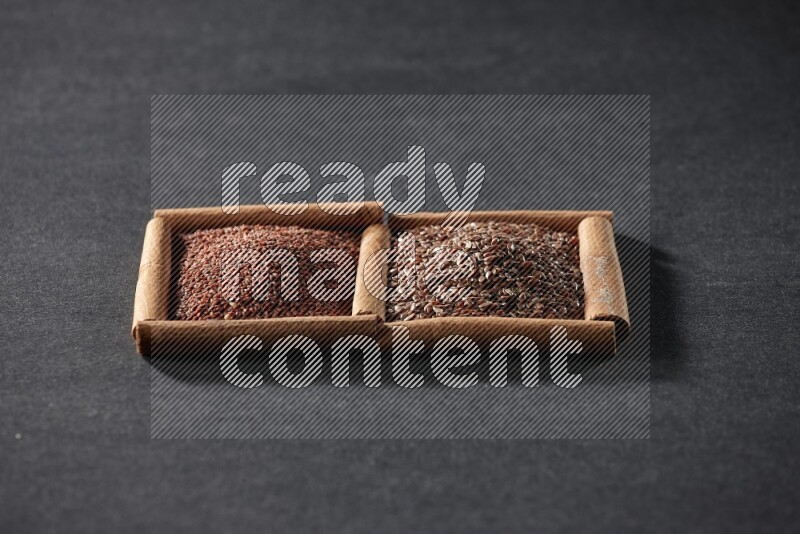 مربعان من أعواد القرفة ممتلئان بحب الرشاد وبذور الكتان علي خلفية سوداء