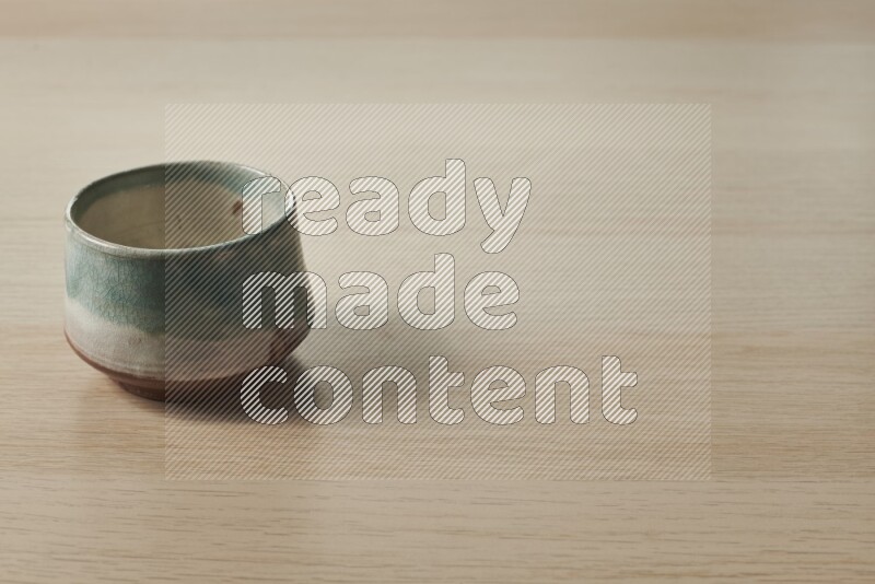 A multicolored pottery bowl on light wooden background