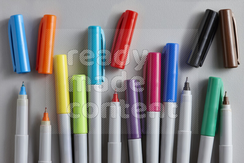 An arrangement of coloring pens in different colors on grey background
