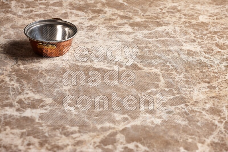 A small copper pot on beige marble background