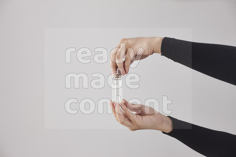 A woman in black abaya holding different glassware in different positions