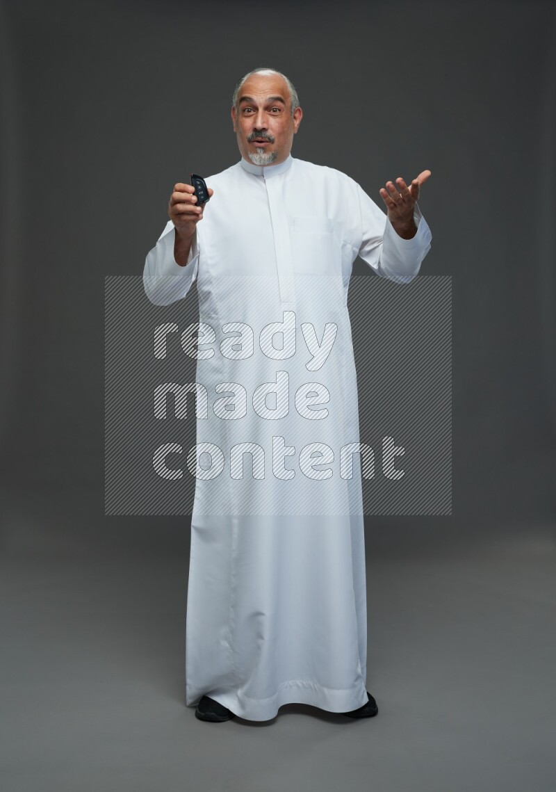 Saudi man without shomag Standing holding car key on gray background