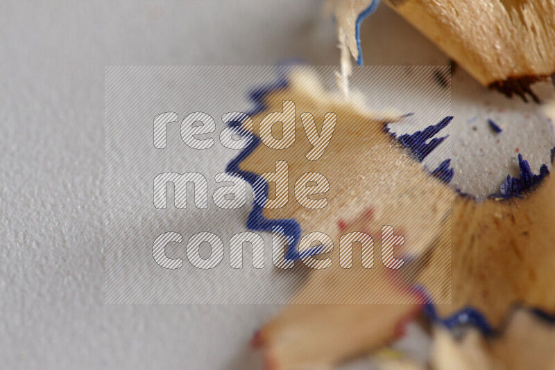A close-up showing a small pile of pencil shavings with varied color edges on grey background