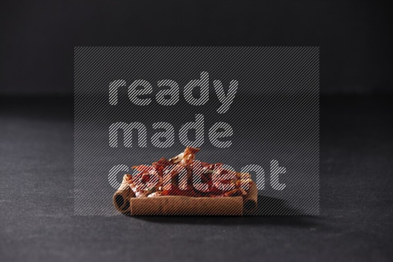 أربعة من أعواد القرفة مكونة شكل مربع بداخلها فلفل حار علي خلفية سوداء