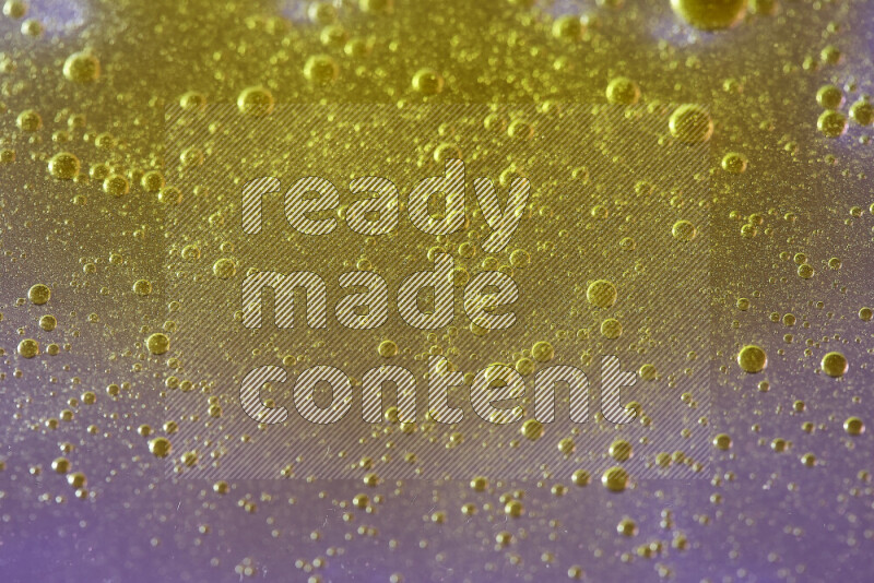 Close-ups of abstract yellow watercolor drops on oil Surface on pink background