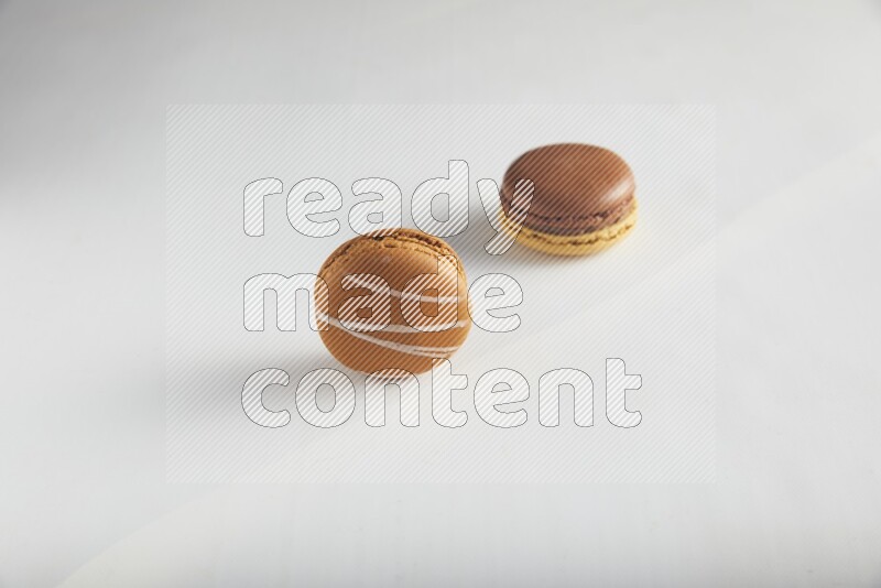 45º Shot of of two assorted Brown Irish Cream, and Yellow, and Brown Chai Latte macarons on white background