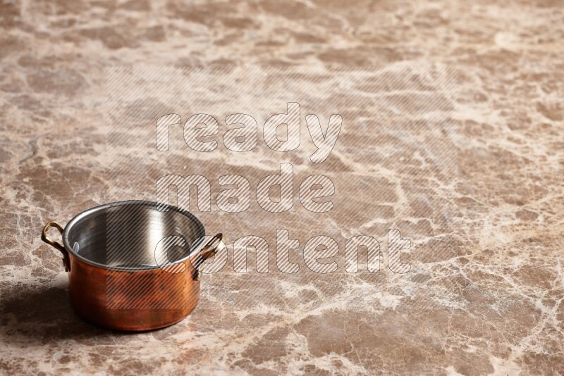 A small copper pot on beige marble background