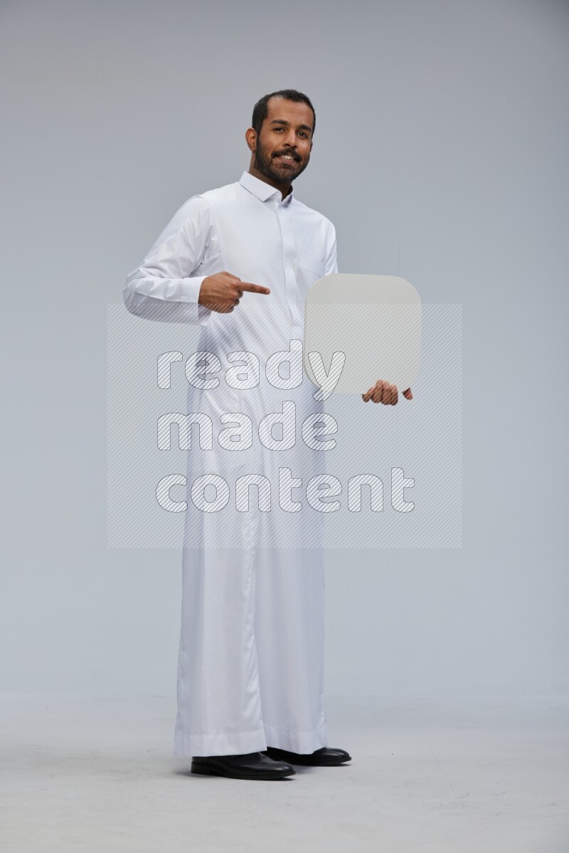 Saudi man wearing Thob standing holding social media sign on Gray background