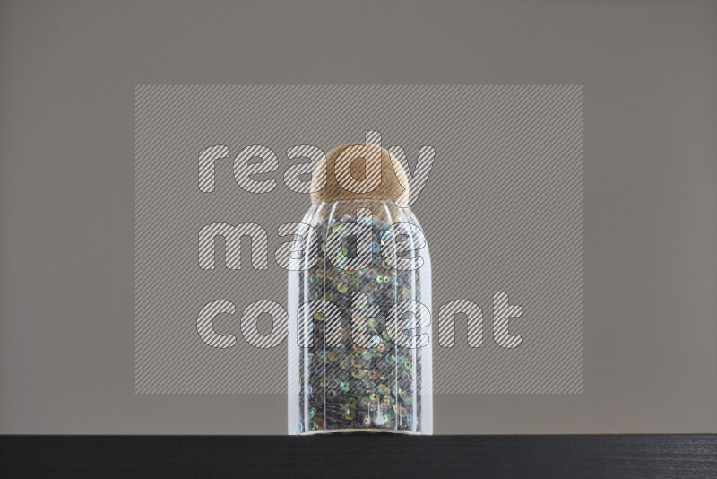 Sequins in a glass jar on black background