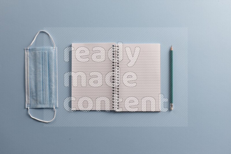 A blank open notebook with different school supplies on blue background
