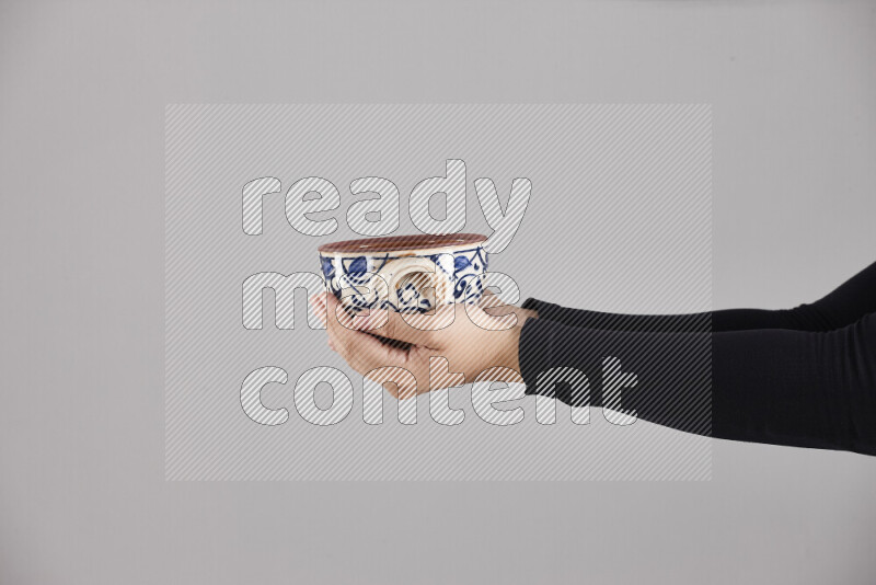 A woman in black abaya holding different pottery essentials in different positions
