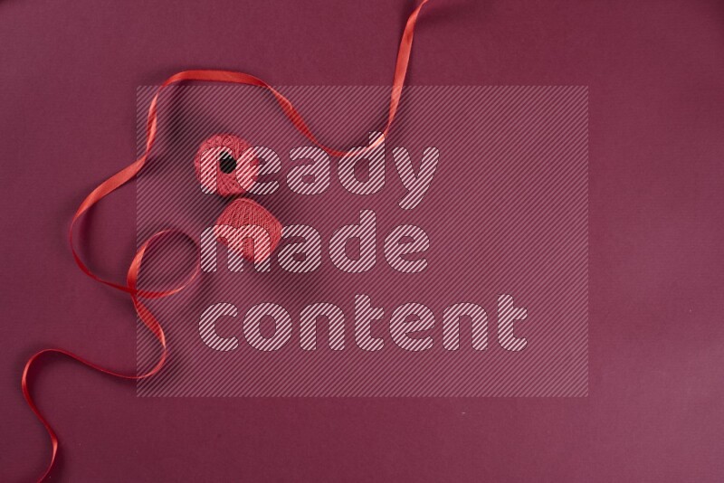 A red collection of sewing and tailoring tools arranged on a red background