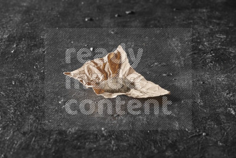 Black pepper powder on crumpled paper on a textured black flooring