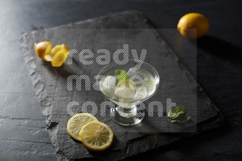 A glass of lemon juice with a lemon slice on black background