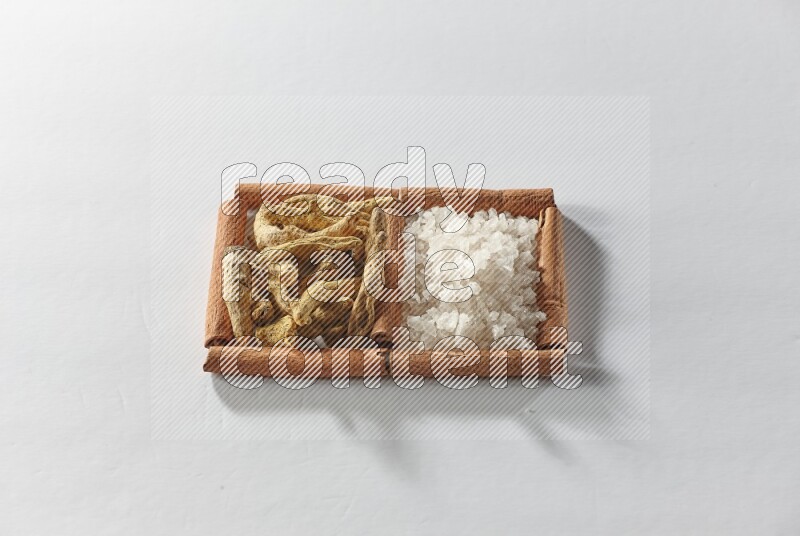 2 squares of cinnamon sticks full of turmeric fingers and white salt on white flooring