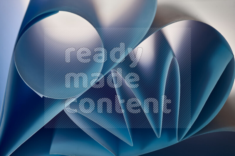 An artistic display of paper folds creating a harmonious blend of geometric shapes, highlighted by soft lighting in blue tones