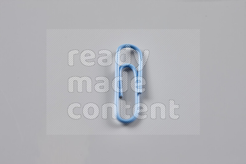 Blue paper clips isolated on a grey background