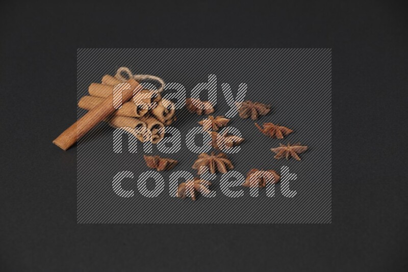 Cinnamon sticks stacked and bounded and star anise on black background