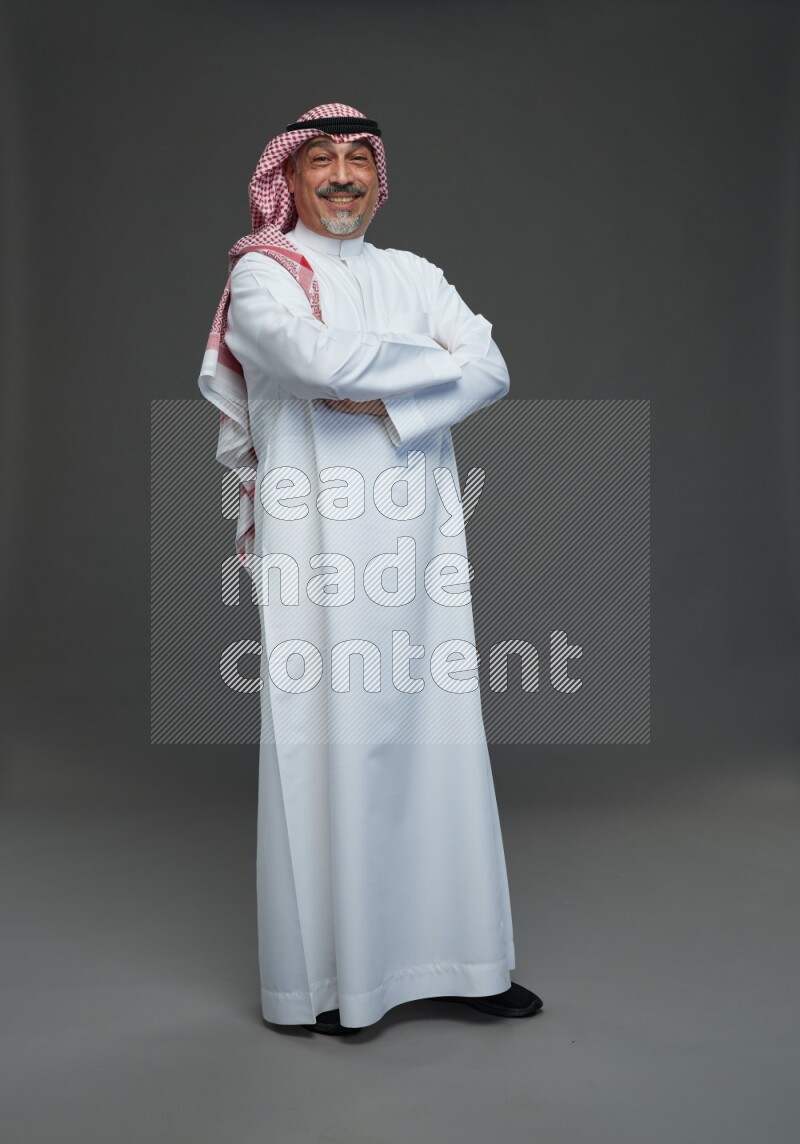 Saudi man with shomag Standing Interacting with the camera on gray background