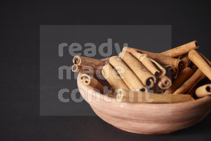 Cinnamon Sticks in a wooden bowl on black background