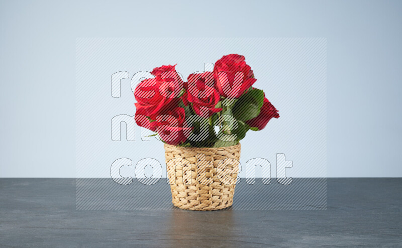 Vibrant red roses in a wicker basket on black marble background
