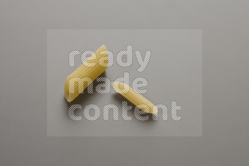 Penne pasta with other types of pasta on grey background