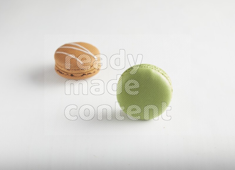 45º Shot of of two assorted Brown Irish Cream, and Green Pistachio macarons on white background