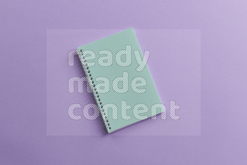 A blue notebook with school supplies on purple background