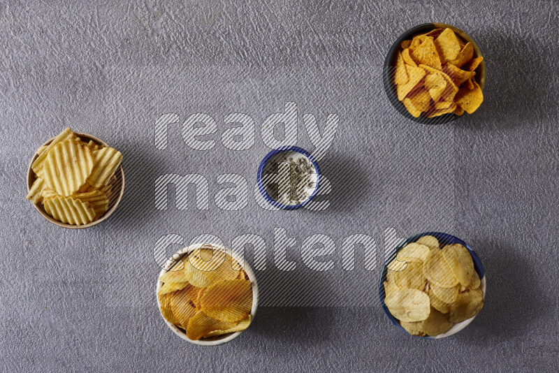 Assorted snacks in pottery bowls on grey background