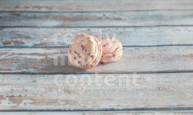 45º Shot of two pink orange blossom macarons on light blue wooden background