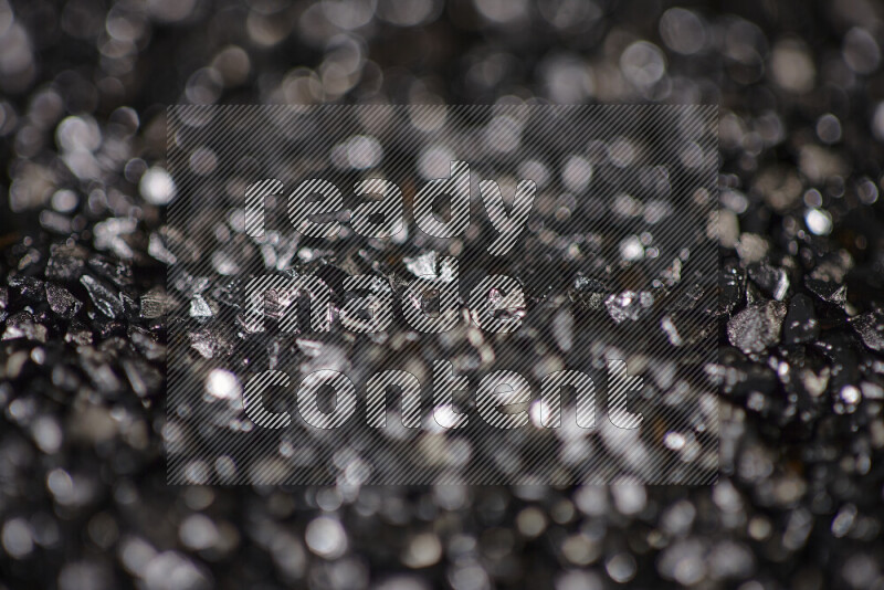 Black shimmering fragments of glass scattered on a black background