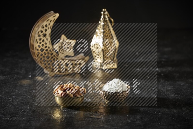 Nuts in a metal bowl with desiccated coconuts beside golden lanterns in a dark setup