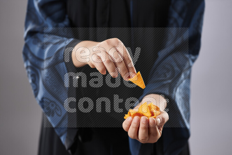 Woman in abaya holding different kinds of snacks in different positions