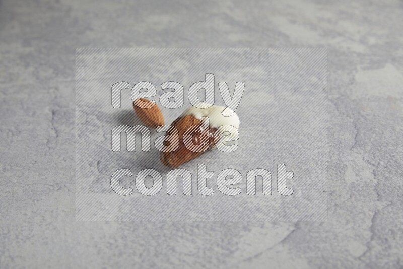 Almond stuffed date coved with white chocolate on a light grey background