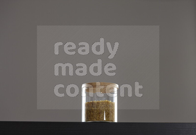 Coarse bulgur in a glass jar on black background