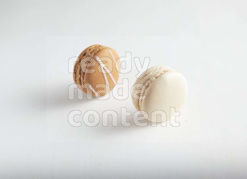 45º Shot of of two assorted Brown Irish Cream, and White Caramel fleur de sel macarons on white background