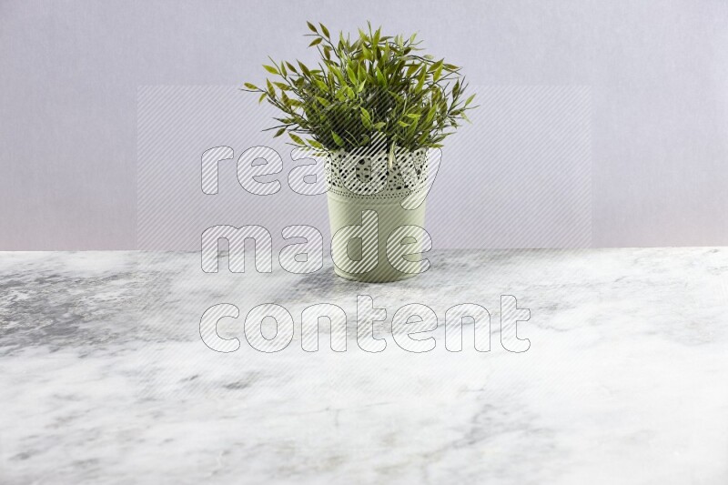 Artificial plant in green decorative pot on grey marble background
