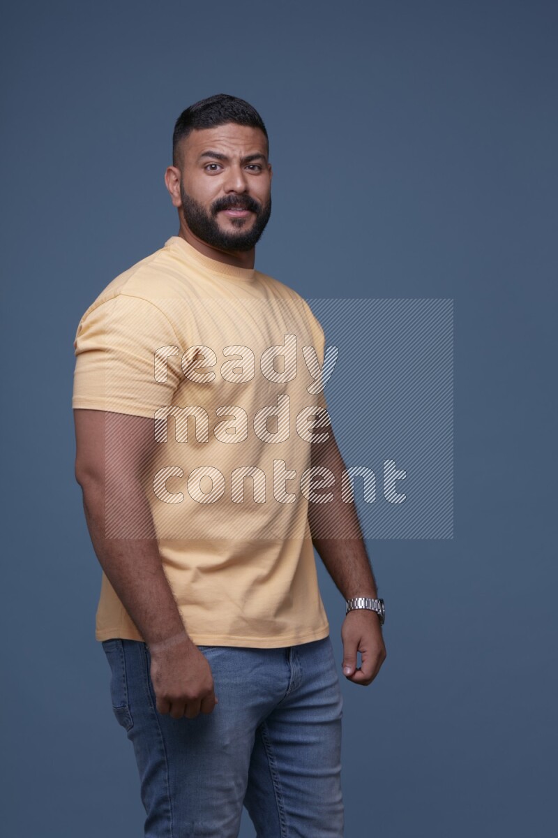 رجل يرتدي قميص اصفر بأكمام قصيرة وبنطال جينز ازرق يقف بأوضاع مختلفة