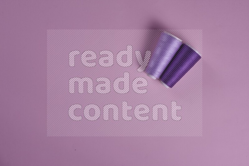 مجموعة من أدوات الخياطة والتفصيل أرجوانية وزهرية اللون على خلفية زهرية